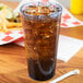 A blue Carlisle plastic tumbler filled with soda and ice on a table with fries.