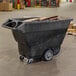 A black Rubbermaid tilt truck for industrial trash.