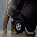 A man using a Rubbermaid tilt truck to move a large black trash cart.