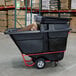 A black Rubbermaid hinged dome lid on a large black tilt truck.