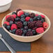 A tan GET SuperMel bowl filled with berries on a white napkin.