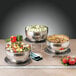 A group of Bon Chef triple wall cold wave bowls filled with food on a table.