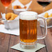 A Carlisle plastic beer mug filled with beer on a table