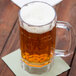 A Carlisle plastic beer mug filled with beer on a napkin.