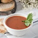 A Carlisle white polycarbonate soup bowl with basil leaves in it.