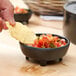 A person dipping a chip into a bowl of salsa.