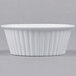 A close up of a white Carlisle fluted plastic ramekin.