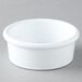 A Carlisle white plastic ramekin on a gray surface.