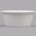 A close up of a white Carlisle fluted plastic ramekin.