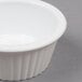 A white Carlisle fluted plastic ramekin on a gray surface.