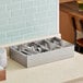 A Vollrath stainless steel 4-compartment cutlery box filled with silverware.