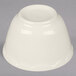 An Ivory (American White) china bouillon cup with a scalloped edge and gold band on a gray surface.