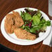 A white Creative Converting paper plate with fried chicken and salad.