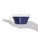 A hand holding a Carlisle cobalt blue plastic ramekin with a smooth finish.