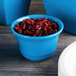 A Tablecraft sky blue cast aluminum bowl filled with cranberries.