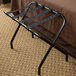 A CSL black metal folding luggage rack with black straps.