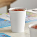 A white Creative Converting paper cup filled with a drink.