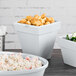 A Tablecraft gray cast aluminum square condiment bowl with green vegetables in it on a counter in a salad bar.