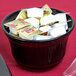 A black cast aluminum Tablecraft condiment bowl filled with candy on a hotel buffet table.