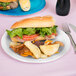 A sandwich and chips on a Creative Converting white paper plate.