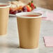 Two gold Creative Converting paper cups filled with a pink drink.