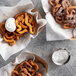 A sieve with white powder on top of a group of Carnival King Funnel Cakes in baskets.