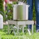 A person standing next to a large metal pot on a Backyard Pro stainless steel outdoor stove.