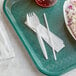 A green tray with a white plastic spork, straw, and napkin on it.