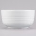 A white Tablecraft cast aluminum fruit bowl with a white rim.