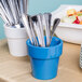 A Tablecraft sky blue cast aluminum round condiment bowl with silverware in it.