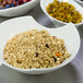 A white porcelain bowl filled with granola and fruit.