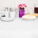 A table set with white table cover, plates, and utensils.