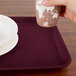 A hand holding a paper cup over a Cambro tray.