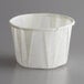 A white Genpak paper souffle cup on a gray surface.