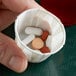 A hand holding a Genpak souffle cup filled with pills.