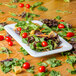 A white Carlisle 1/3 size food pan filled with salad on a table.