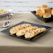 A black GET Siciliano square plate with cookies and silverware on it.