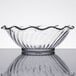 A close up of a Carlisle clear glass bowl with a wavy edge.