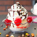 A Carlisle clear tulip berry dish filled with a dessert topped with whipped cream and cherries.