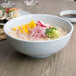 A bowl of rice with vegetables in a Thunder Group Blue Jade melamine bowl.