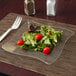 A Fineline clear plastic square plate with a salad on it.