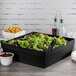 A salad in a black Tablecraft cast aluminum bowl on a table.