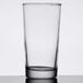An Anchor Hocking Regency highball glass with a straw on a table.