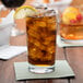 A glass of ice tea with a lemon slice on top in an Anchor Hocking Regency highball glass.