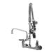 A T&S chrome wall mounted pre-rinse faucet with a hand held sprayer.