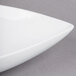 A white Tablecraft cast aluminum triangle display bowl with curved edges.