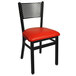 A black chair with a red seat cushion.