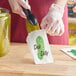 A person putting a pickle into a white Carnival King paper bag.