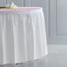 A white Creative Converting plastic table skirt on a table.