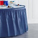 A table with a navy blue plastic table skirt on it.